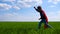 Charming boy running on the green grass. A child in a red cloak depicts the flight of Superman.