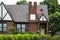 Charming brick house with landscaping and lime green door with wreath and American flag flying with lush trees behind