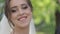 Charming bride in gorgeous wedding dress hold bouquet and stand in front of blooming trees