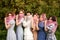 Charming bride in white dress with white veil and bridesmaids with pink veils lined up in a row, smiling and playfully