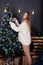 charming brunette woman in knitted sweater near christmas tree with blue decor. happy new year theme. cozy holidays and