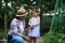 Charming Caucasian baby girl helping her mom harvesting cucumbers in a family eco farm. Gardening, agribusiness, farming