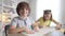 Charming Caucasian boy looking at camera and smiling with blurred girl drawing at background. Portrait of cute confident