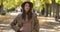Charming Caucasian lady in elegant brown hat and coat posing on the background of autumn park. Positive European girl