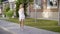 Charming cheerful woman in casual dress walking along sidewalk and looking at camera.