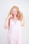 Charming chubby blonde girl in pink pretty nightgown stretch hands on white background in Studio