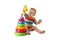 Charming cute baby in overalls plays with a colored plastic pyramid sitting on a white background. A child collects a colored