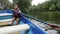 Charming cute boy sitting in boat on lake in autumn. Adorable little child sailing on wooden boat on lake in park with green trees