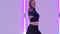 Charming dancer in black leotard performing acrobatic contemp dance elements against the backdrop of bright neon lights