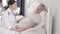 Charming doctor takes care of a disabled senior man in bed