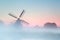 Charming Dutch windmill in dense sunrise fog