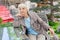 Charming elderly gray-haired woman relaxing sitting in the garden