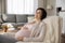 Charming expectant mother relax in comfy chair at living room