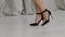 Charming female legs in black high heel shoes close up. A woman in slow motion walks on the white floor against the