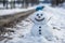 Charming and friendly snowman with bright blue eyes standing alone by the scenic roadside