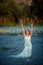 Charming ginger head bride in the wedding dress is splashing water while standing in the middle of the river during the