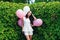 Charming girl with balloons in green hedgerow