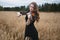 Charming girl in a black dress enthusiastically playing the violin in a wheat field