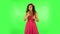 Charming girl looks around, whispers the secret and making a hush gesture. Green screen at studio