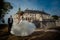 The charming gorgeous bride is dancing and spinning round near the handsome groom at the background of the old castle.