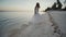 Charming and happy bride in a white dress dancing barefoot on the sandy shore of a tropical beach. Ocean. The palms