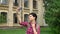 Charming happy college student with short black hair taking selfie and smiling, standing in park near university