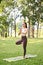 Charming healthy Asian woman practicing Tree pose, training yoga in the garden