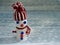 Charming homemade snowman from reel, tennis ball in bright woolen hat with scarf on light background decorated with snowflakes.