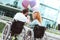 Charming husband and wife in wheelchairs beaming while holding balloons