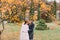 Charming just married couple embracing in the beautiful autumn park under tree with yellow leaves