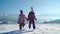 Charming kids in outwear running on snowy terrain with beautiful mountains on background in sunshine