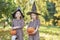 Charming kids in witch costume holding halloween pumpkins