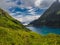 Charming lake with amazing deep colorful water and wild clouds on sky.