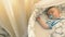 Charming little boy with dummy is sleeping in a crib