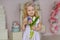 Charming little girl blonde in a dress is holding flowers and sm