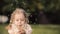 Charming little girl blowing dandelion while walking