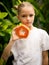 Charming little girl with fresh papaya. Caucasian girl holding slice of papaya fruit in front of her neck. Selected focus. Green