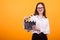 Charming little girl holding clappers, looking at camera and smiling, standing on yellow background