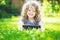 Charming little girl lying on the grass and holds in hands tablet