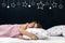 Charming little girl of preschool age sleeps in bed on a pillow with stars. Time to sleep. Abstract background about