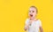 Charming little girl in white t-shirt cleaning teeth with colorful kids toothbrush on a yellow studio background. Hygiene concept