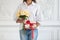 Charming longhaired woman holds gift box and bouquet. Selective focus