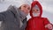 Charming mother with a child in a red winter suit walks along the street