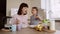 Charming mother and her little daughter feed each other with chocolate corn balls with milk