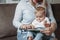 Charming mother showing images in a book to her cute little son at home sitting on the couch