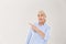 Charming old lady with silver hair, pointing with finger, looking aside