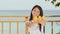 A charming philippine schoolgirl girl in a white dress and long hair positively poses with a mango in her hands. The sun