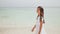 A charming philippine schoolgirl in a white dress is walking along a white sandy beach. Enjoying the tropical scenery
