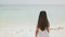 A charming philippine schoolgirl in a white dress is walking along a white sandy beach. Enjoying the tropical scenery