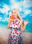 Charming plump blonde in blue pin up dress stands with a piece of watermelon and enjoys rest and a snack